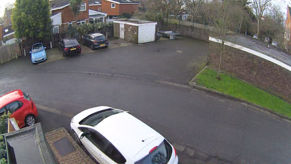 View from our security camera: section of road, 5 parked cars, 2 garages